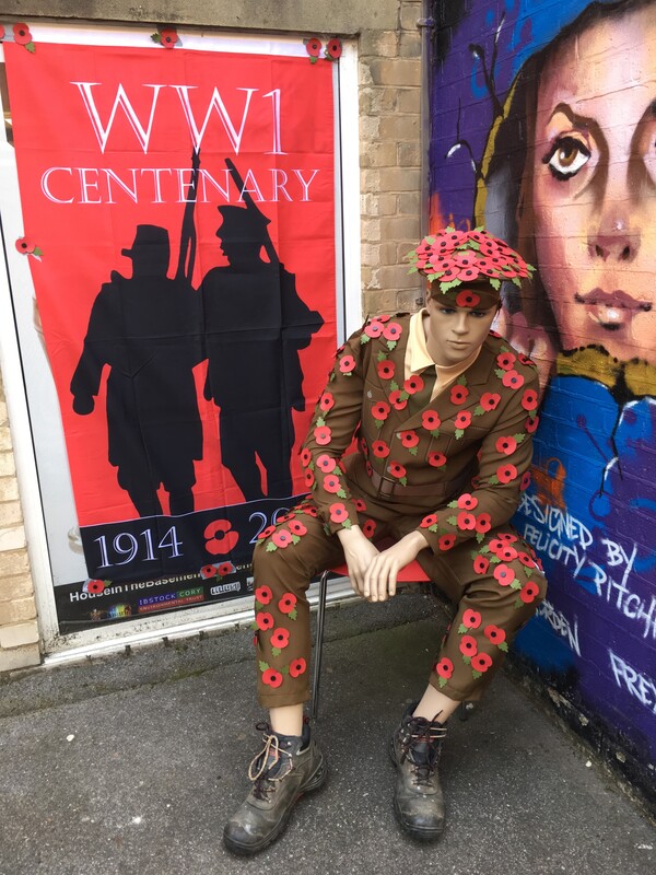 Image shows Tommy the Soldier mannequin decorated in a WW1 uniform covered with Poppies to commemorate the centenary of WW1, outside House in the Basement Youth Cafe. 
